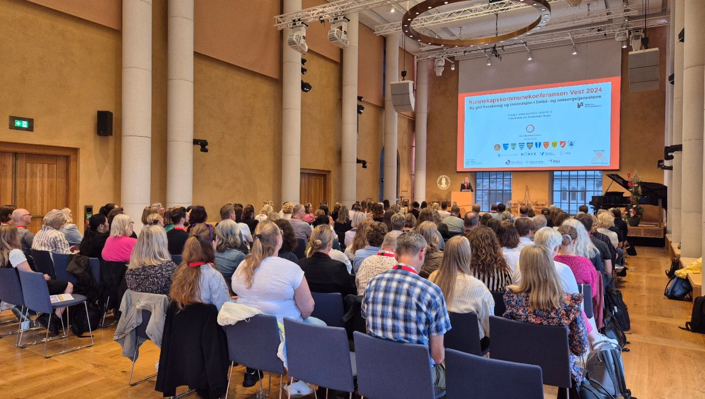 Bilde av publikum og scene i universitetsaulaen under Kunnskapskommunekonferansen 5. september 2024