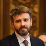 Profilbilde av Statsråd Jan Christian Vestre, fra skuldre og opp, ikledd dress, brun bakgrunn