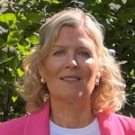 Portrettbilde av Katrine Rutgerson, blondt halvlangt bølgete hår, smil, hvit topp og rosa blazer