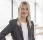 Blondt hår, smilende dame, grå blazer, hvit t-skjorte. Lys bakgrunn